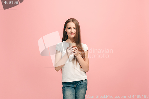 Image of The happy teen girl standing and smiling against pink background.