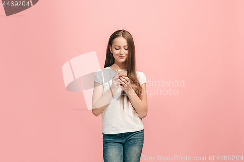 Image of The happy teen girl standing and smiling against pink background.