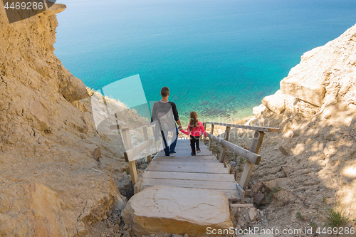 Image of Dad and daughter go down the steep mountain stairs to the sea