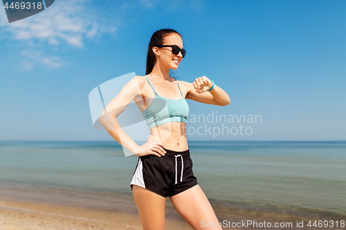 Image of happy woman with fitness tracker on summer beach