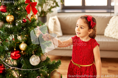 Image of little girl decorating christmas tree at home