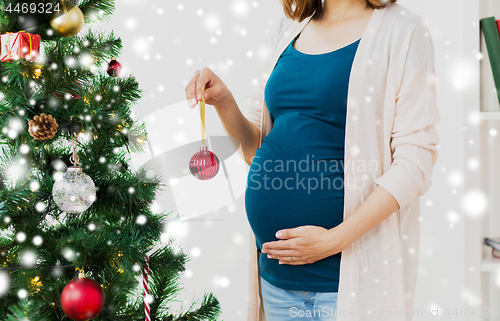 Image of pregnant woman decorating christmas tree