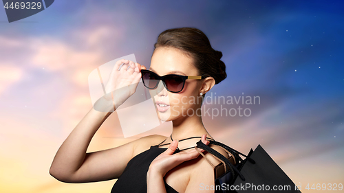 Image of happy woman in black sunglasses with shopping bags