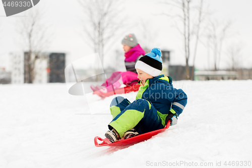 Image of kids sliding on sleds down snow hill in winter