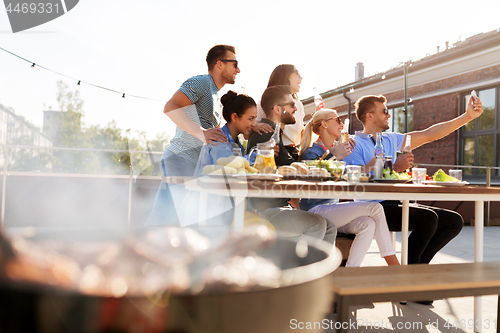 Image of happy friends taking selfie at rooftop party