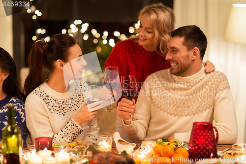 Image of happy friends drinking red wine at christmas party