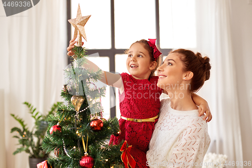 Image of mother and daughter decorating christmas tree