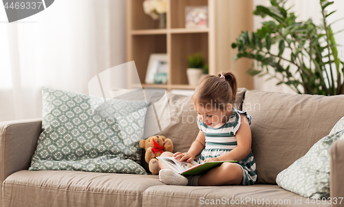 Image of little girl reading book at home