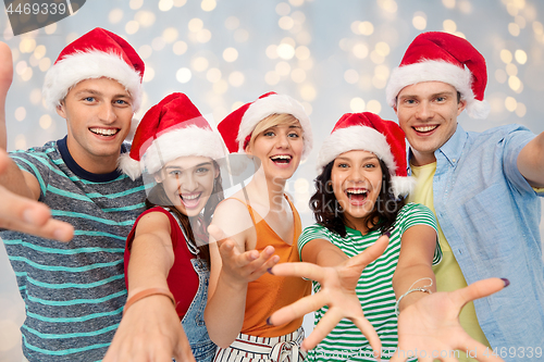 Image of happy friends in santa hats celebrating christmas