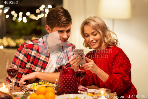 Image of couple with smartphone at home christmas dinner