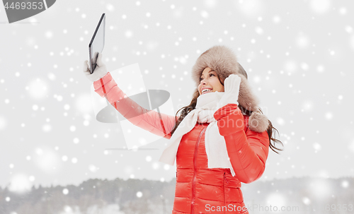 Image of woman in winter fur hat with tablet pc outdoors