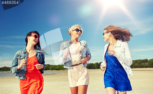 Image of group of smiling women in sunglasses on beach