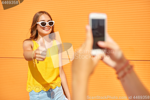 Image of teenage girl photographing friend by smartphone