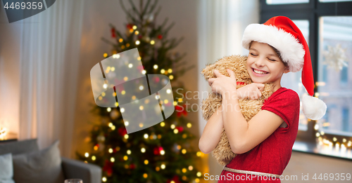 Image of girl in santa hat with teddy bear on christmas