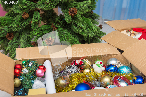 Image of Christmas tree decorations in a box in front of an artificial Christmas tree