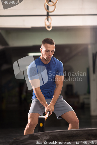 Image of man workout with hammer and tractor tire