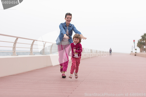 Image of mother and cute little girl on the promenade by the sea