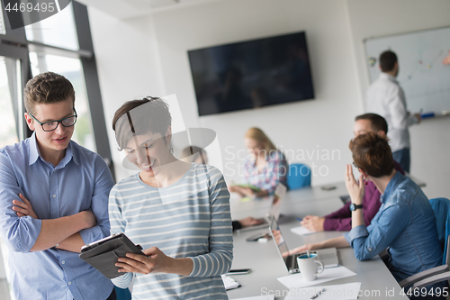 Image of Two Business People Working With Tablet in office