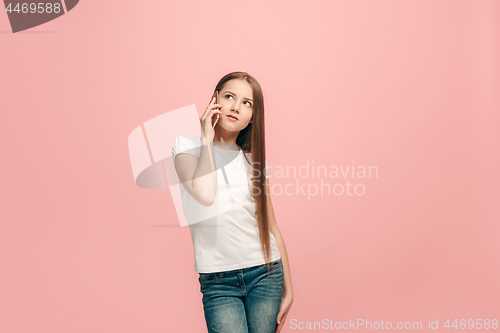 Image of The happy teen girl standing and smiling against pink background.