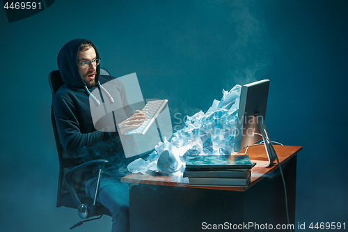 Image of Young stressed handsome businessman working at desk in modern office shouting at laptop screen and being angry about spam