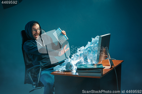 Image of Young stressed handsome businessman working at desk in modern office shouting at laptop screen and being angry about spam