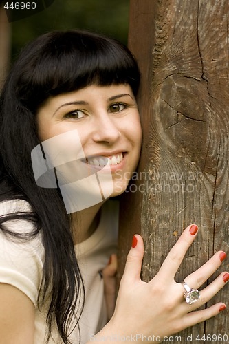 Image of happy girl hiding behind a tree