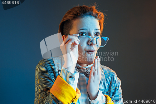 Image of The young attractive woman looking suprised isolated on dark blue