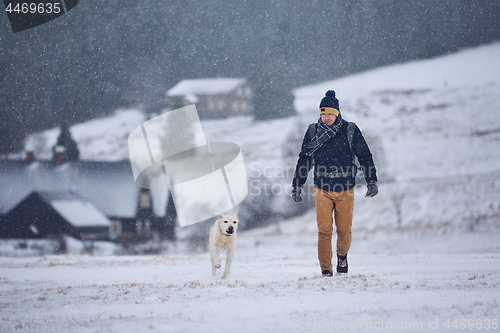 Image of Man playing with dog in winter landscape