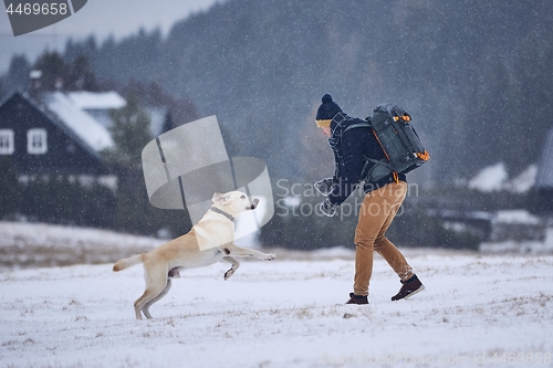 Image of Man playing with dog in winter landscape