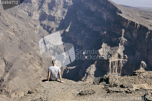 Image of Tourist resting on the edge of cliff