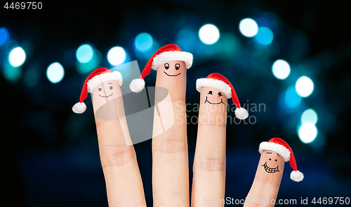 Image of close up of four fingers in santa hats over lights