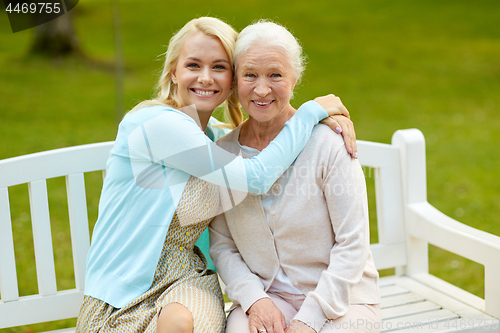 Image of daughter with senior mother hugging on park bench