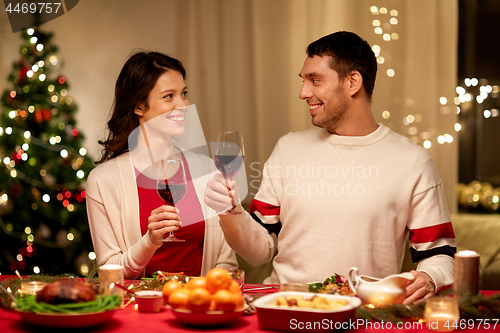 Image of happy couple drinking red wine at christmas dinner