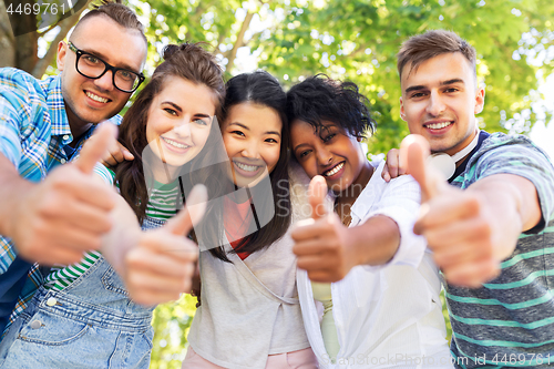 Image of happy friends making thumbs up in park