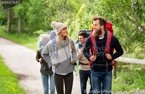 Image of happy friends or travelers hiking with backpacks