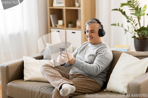 Image of man with smartphone and headphones at home