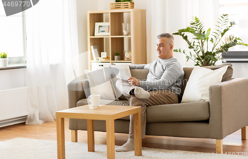 Image of man reading newspaper at home