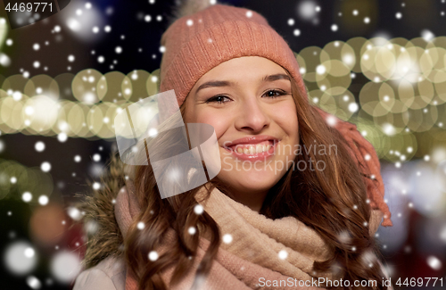 Image of happy young woman over christmas lights in winter