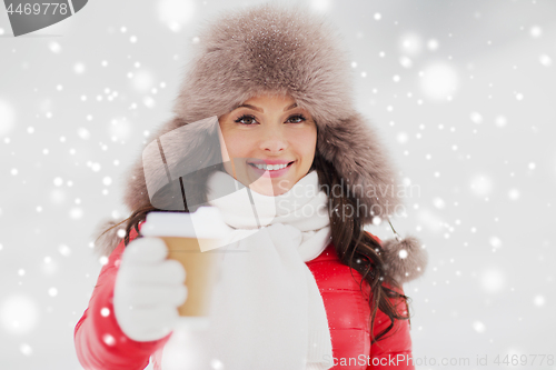 Image of happy woman in winter fur hat with coffee outdoors