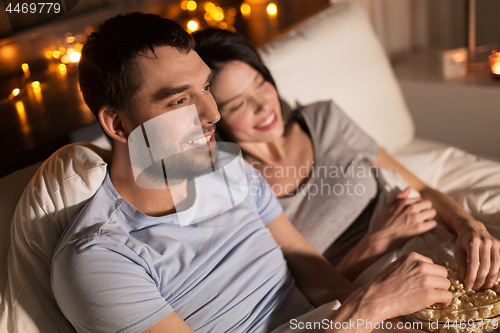 Image of couple with popcorn watching tv at night at home