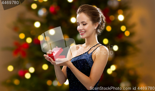 Image of woman with red gift box over christmas tree lights