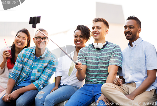 Image of friends taking picture by on selfie stick in city