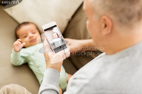 Image of father photographing baby by smartphone