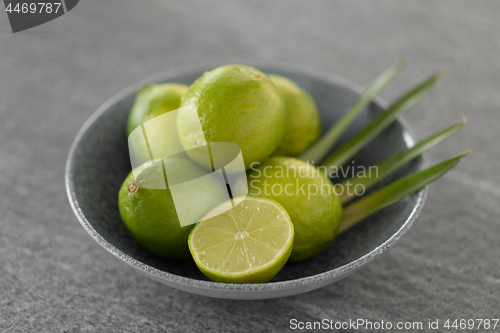 Image of close up of limes in bowl on slate table top