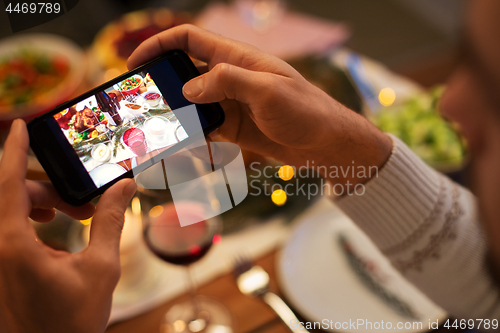 Image of hands photographing food at christmas dinner