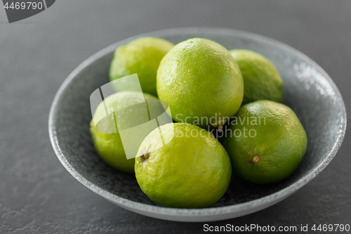 Image of close up of whole limes in bowl on slate table top