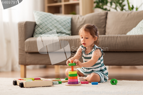 Image of happy baby girl playing with toy blocks at home