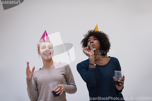 Image of smiling women in party caps blowing to whistles