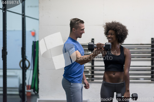 Image of black woman doing bicep curls with fitness trainer