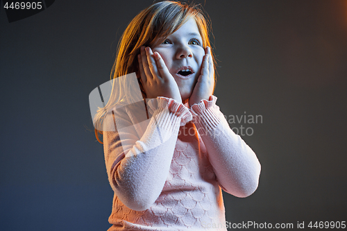 Image of The young attractive teen girl looking suprised isolated on dark blue